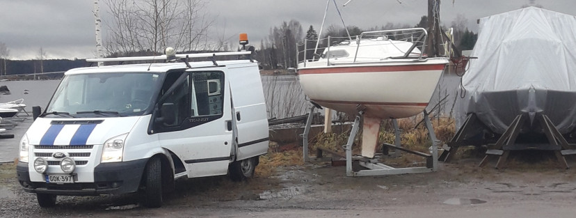 Huoltoauton vieressä vene maalla telineessä